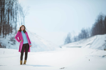 A shallow focus shot of a female wearing fashionable winter clothes in the snowの写真素材
