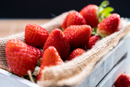 A selective focus shot of fresh strawberries on burlap and in a wooden boxの写真素材