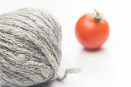 A selective focus shot of a wool ball and tomato isolated on a white backgroundの写真素材
