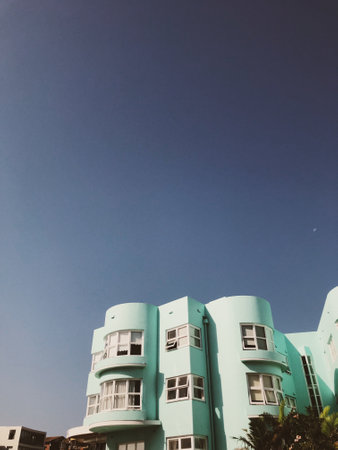 A vertical shot of a beautifully arcitectured turquoise building facade under a perfectly clear