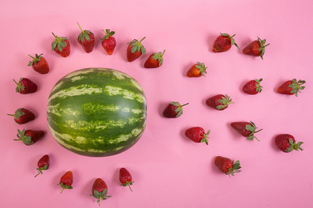 A top view of beautiful composition made of fresh strawberries and watermelon on a pink backgroundの写真素材