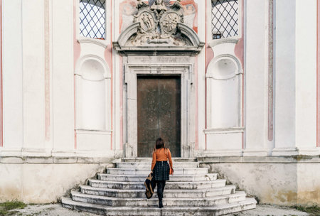 A back view of a traveler female walking up stairs of an old buildingの写真素材