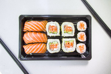 A top view of California sushi rolls with chopsticks set in a black containerの写真素材