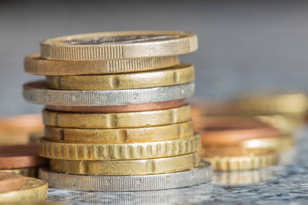 A closeup shot of euro coins stacked on each other in different positions on a blurred backgroundの写真素材