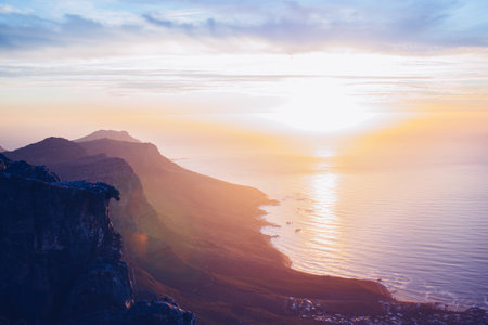 A majestic nature scene of bright sitting down sunset sun and immense cliffs on the coastline