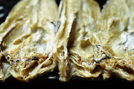 A closeup of appetizing dried fish on a black surface
