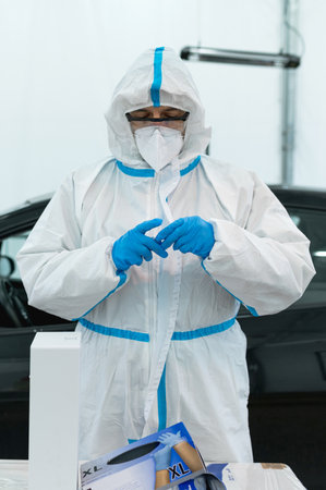A vertical shot of a nurse in a personal protective suit preparing to take a swabの写真素材