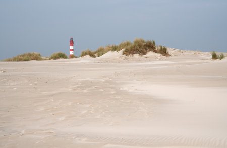A mesmerizing view of the sand dunes of Amrum with the lighthouse in North Frisia, Germanyの写真素材