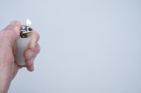 A closeup shot of a person holding a lighter over a grey surface