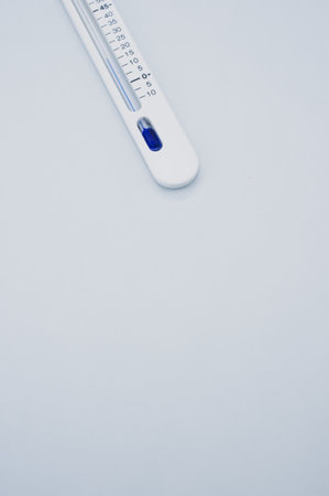 A vertical shot of a medical thermometer on a grey surface