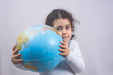 A closeup portrait curious child holding an earth globe map in his handの写真素材