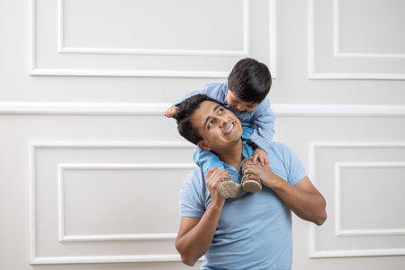 Mexican father and son happily playing at homeの写真素材