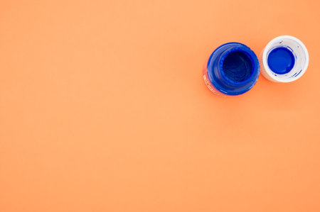 A top view of a small opened can of blue gouache paint isolated on a coral backgroundの写真素材