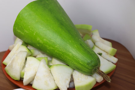 A closeup of sliced bottle gourds on a plate on the table in the kitchenの写真素材