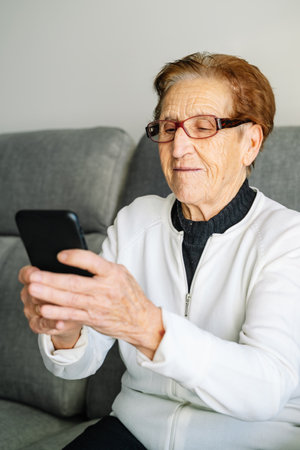 An older woman typing a message on a mobile phone