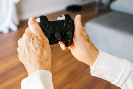 The hands of a senior female using a video game controller while playingの写真素材