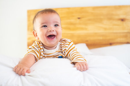 A closeup shot of a cute smiling baby on a bed