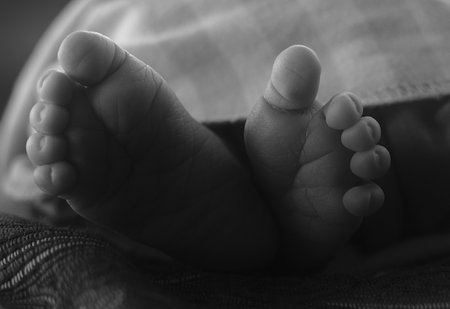 A closeup shot of baby feet on a bed in grayscaleの写真素材