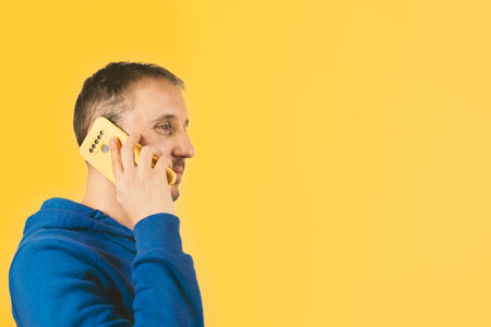 A male talking on his smartphone with a yellow case on a yellow background