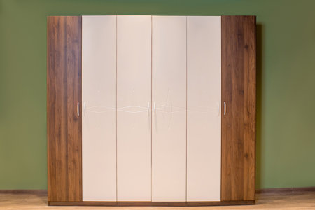 A closeup shot of a wooden and white wardrobe against a green wallの写真素材