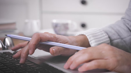 A female working from home using a laptop and taking notes in a notebook