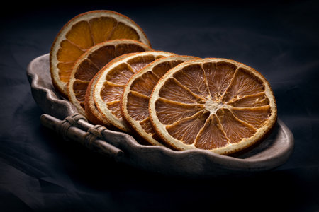 Dried orange slices on black background. Ingredients for cooking or christmas decoration. Natural fruit chips without sugar and spices.の写真素材