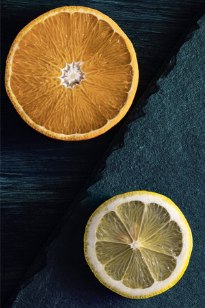 Orange and lemon slices on dark teal wood and stone background decoration.の写真素材