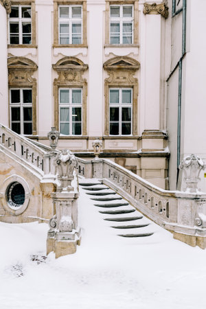 A vertical shot of an old style building and wide staircase on a winter day with snow on the groundの写真素材