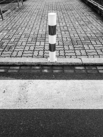 A vertical grayscale shot of a sidewalk close to the streetの写真素材