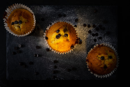 An overhead shot of tasty muffins with chocolate chips on a black sの写真素材