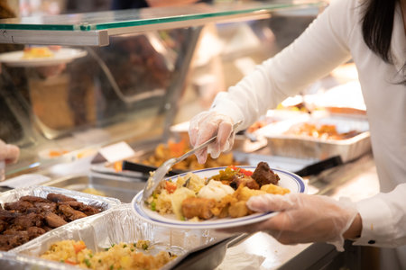 A woman wearing plastic gloves putting food on a plate - celebration and meal conceptの写真素材