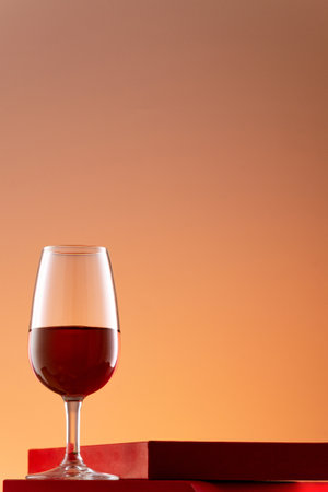 A vertical shot of a small Champagne glass with red alcohol isolated on an orange backgroundの写真素材