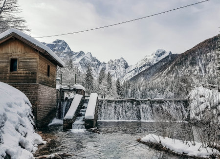 Falling water on small dam on lake in mountains. Fusine lakes, Italy. Alps, alpine, no people,...