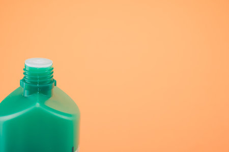 A closeup shot of a green bottle with paint isolated on orange backgroundの写真素材