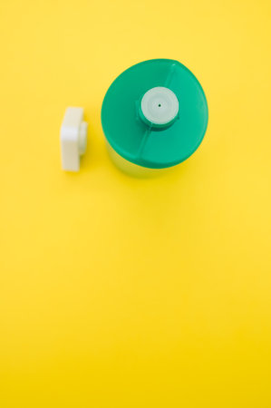 A vertical top view of a green bottle with paint isolated on a yellow backgroundの写真素材
