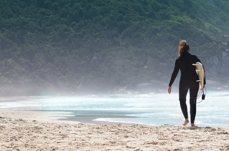 A female holding a surfing board on the beach getting ready to surfの写真素材