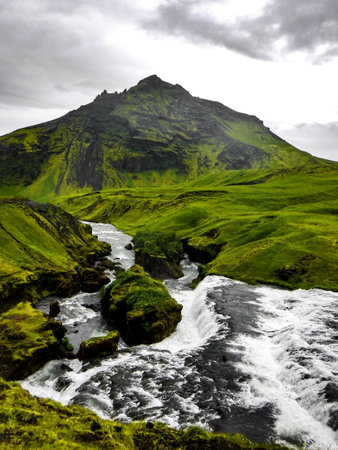 A vertical shot of a river in a green mountain against the cloudy sky - perfect for wallpaperの写真素材