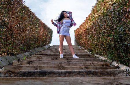A Caucasian young woman in a white skirt posing on the stairs