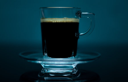 A closeu shot of black coffee with foam on a transparent glassの写真素材