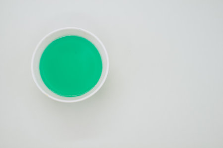 A green liquid watercolor in a white bowl isolated on a grey backgroundの写真素材