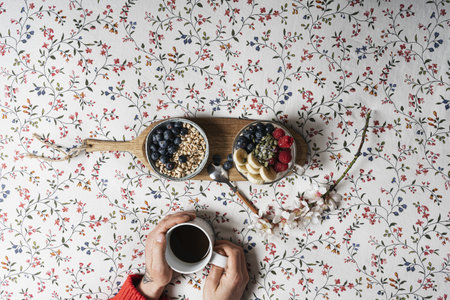 A top view of a person having breakfast with a cup of coffee and yogurt with fruits on a bedの写真素材