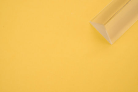 A closeup shot of a triangular glass prism isolated on yellow backgroundの写真素材
