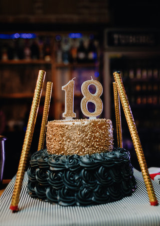 A closeup of a creamy delicious birthday cake with number 18 candles on top