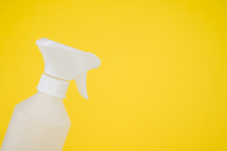 A closeup shot of a white plastic spray bottle isolated on yellow backgroundの写真素材