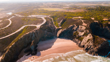 A landscape of the beach surrounded by cliffs and sea on a sunny day in Algarve, Portugalの写真素材