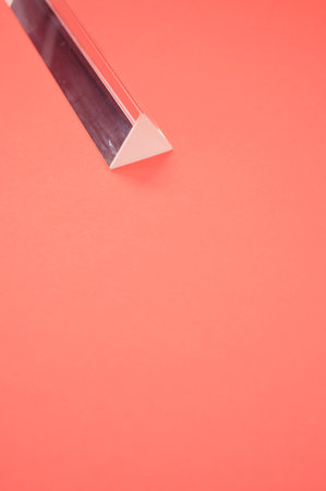 A closeup shot of a triangular glass prism isolated on a red backgroundの写真素材