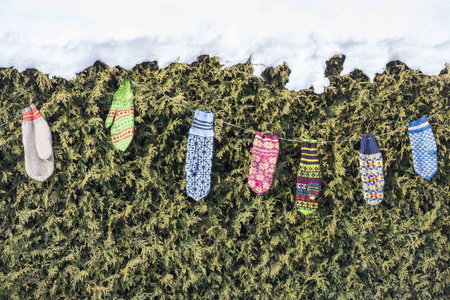 A closeup shot of knitted colorful mittens hanging from a rope outside on a winter dayの写真素材