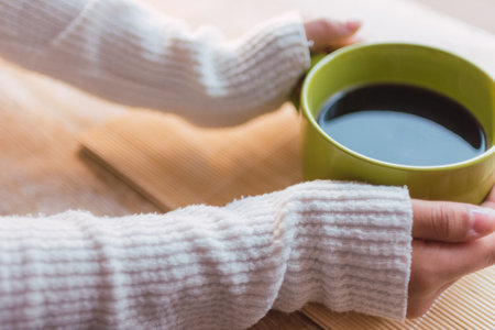 A high angle shot of a female holding a hot cup of coffeeの写真素材