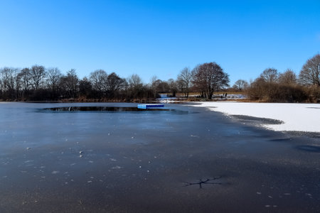 A beautiful view of the frozen lake against the clear blue sky in the parkの写真素材