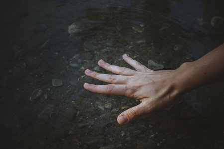 A closeup shot of the hand of a person touching the water of the rivの写真素材